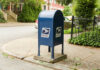 USPS Collapse Imminent — Mail Stops Within Months? Blue USPS mailbox on a residential street corner.