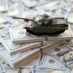 A toy tank placed on stacks of hundred-dollar bills