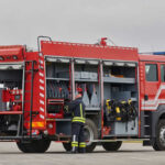 Firefighter accessing equipment on a parked fire truck