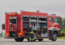 Firefighter accessing equipment on a parked fire truck