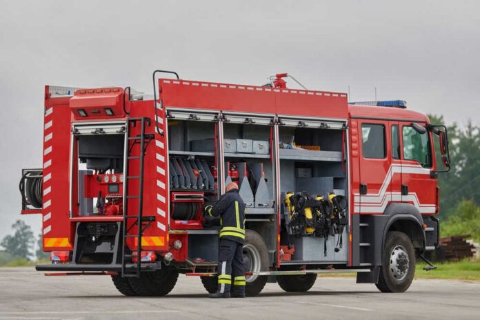 Firefighter accessing equipment on a parked fire truck
