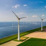 SHOCKING Payout Kills Energy for 1.3M Homes Aerial view of wind turbines along a coastline with fields