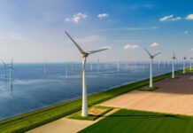 SHOCKING Payout Kills Energy for 1.3M Homes Aerial view of wind turbines along a coastline with fields