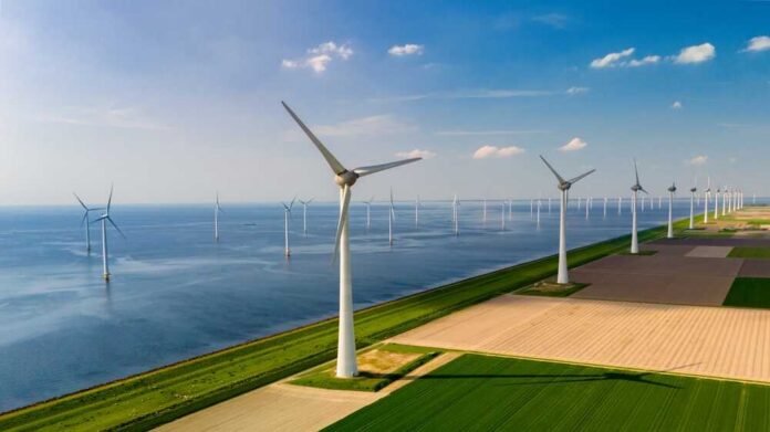 Aerial view of wind turbines along a coastline with fields