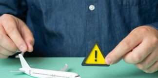 A person holding a warning sign next to a model airplane
