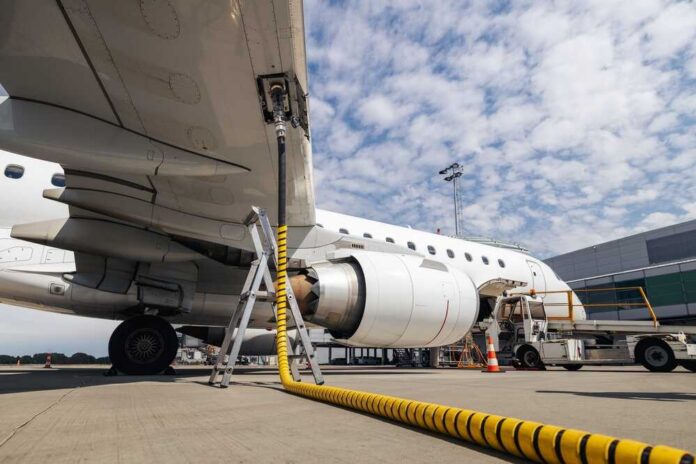 An airplane being fueled at an airport with a visible jet engine