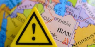 A yellow warning sign placed on a map highlighting Iran