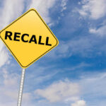 Massive Recall: 10 States Alerted Yellow sign with RECALL text against blue sky.