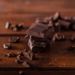 Stack of dark chocolate pieces on a wooden surface