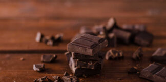 Stack of dark chocolate pieces on a wooden surface
