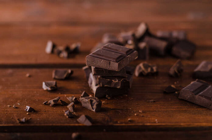 Stack of dark chocolate pieces on a wooden surface
