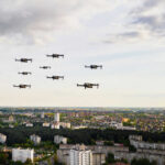 Drone Nearly DESTROYS Passenger Jet Drones flying over a cityscape under cloudy sky.