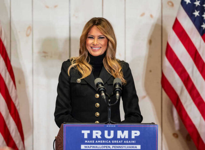 Woman speaking at Trump podium, two American flags present.