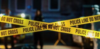 Police tape marking a crime scene with blurred figures in the background