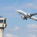 Airlines Coordinate ATTACK on Ordinary Travelers’ Wallets An airplane taking off near an airport control tower