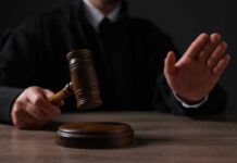 Judge Sabotages Trump Border Crackdown Judge holding gavel, hand raised in courtroom.