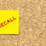 Yellow sticky note with the word 'RECALL' on a corkboard