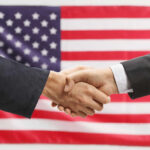 Two hands shaking in front of American flag