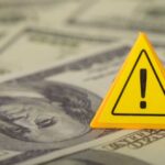 Massive Refund Chaos Just Started A yellow warning sign placed on a background of dollar bills