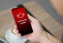 Hand holding a smartphone displaying an earthquake alert notification