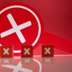 A red magnifying glass with a cross symbol against a red background