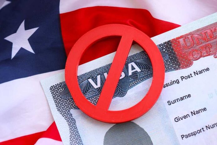 shutterstock_2689070697.jpg A red 'no' symbol over a visa document on an American flag background