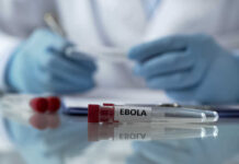 Ebola Nightmare: Six Americans in Danger? Ebola test tubes on lab table with gloved scientist in background