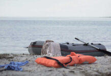 An inflatable boat on the beach with a life jacket and clothes nearby