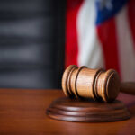 Actor’s Brutal Attack: Shocking Courtroom Drama A wooden gavel resting on a sound block with an American flag in the background