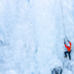American Climber KILLED Moments After Historic Summit A climber in an orange jacket scaling a frozen ice wall