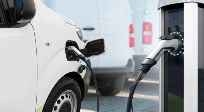 Electric,Delivery,Van,With,Electric,Vehicles,Charging,Station. Electric vehicle connected to a charging station
