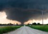 A tornado forming in a rural area with dark storm clouds overhead