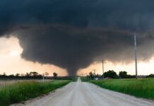 A tornado forming in a rural area with dark storm clouds overhead