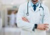 A doctor in a white coat with a stethoscope standing with arms crossed