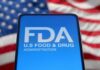 FDA Boss QUITS — Brutal War Exposed Inside Agency FDA logo displayed on a smartphone with an American flag background