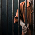 Spy Execution: Hidden Truths Behind the Noose? Man in orange prison uniform behind jail bars.