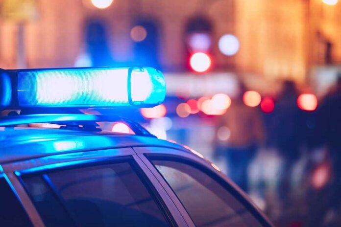Close-up of a police car with blue emergency lights in a city at night