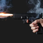 VIDEO: Bullets Hit 12 During American Festival A hand holding a gun with smoke and a flash from the muzzle