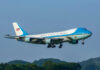 Airplane flying above trees with blue sky background