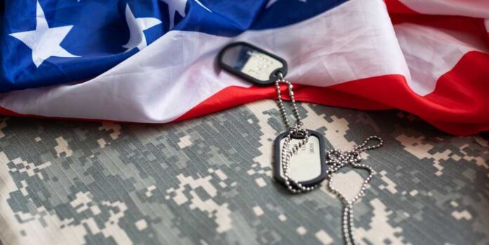 Military dog tags on camouflage fabric with an American flag