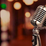 Music Kingpin Gone — Questions Swirl Vintage microphone on a blurred, warm-toned background.