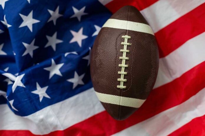 American,Football,Ball.,American,Football,With,American,Flag.,Dark,Background. An American football resting on a background of the American flag