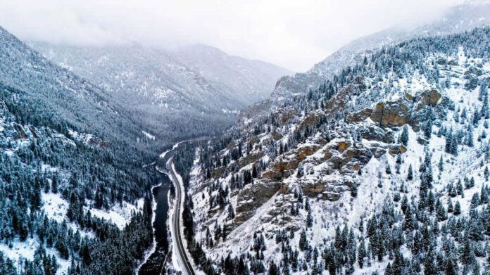 shutterstock_2429292505 Snowy valley with road winding through frozen forest