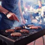 Person grilling burgers at an outdoor barbecue