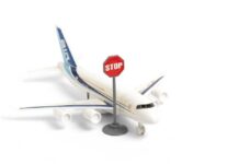 War Fuel Shock Hits U.S. Flights – Routes Canceled A toy airplane next to a stop sign