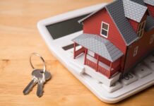 Mortgage Shock: THIS Status Enters Risk Math A miniature red house on a calculator with keys nearby