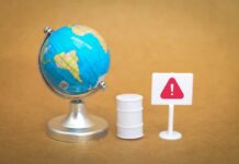 Oil Panic Vanishes Overnight A miniature globe next to a warning sign and a barrel