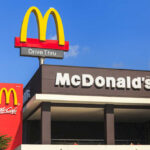 McDonalds drive-thru sign against a blue sky.