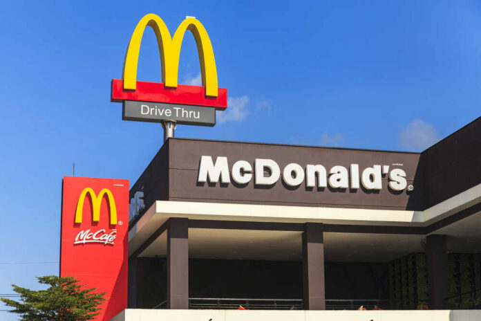 McDonalds drive-thru sign against a blue sky.