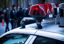 Teen Showdown Ends — Murder, Not Self Defense Police car roof with lights, officers in background.